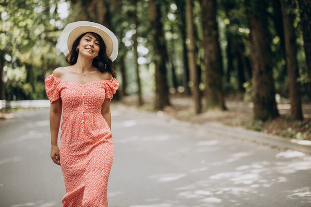 Young woman wearing dress and hat walking in park