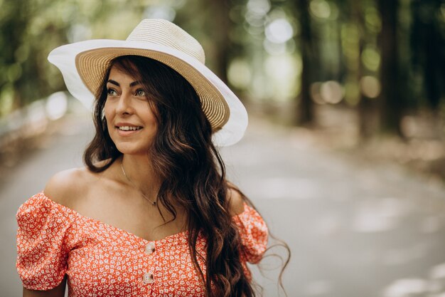 Young woman wearing dress and hat walking in park