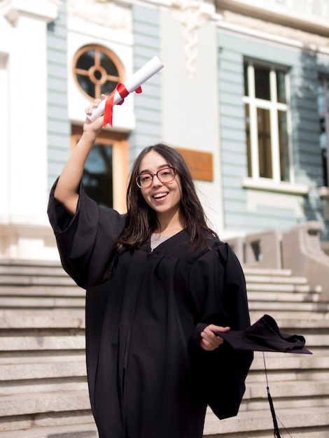 Young woman wearing graduation gown outdoors