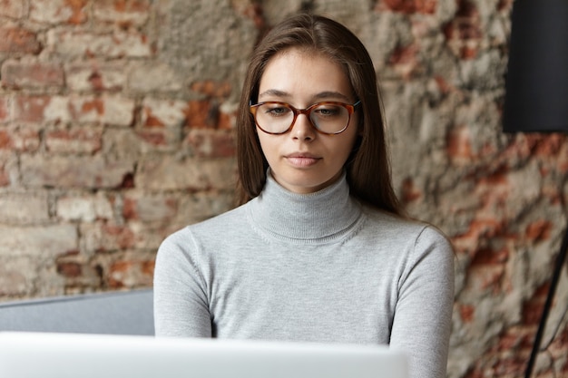 Free photo young woman wearing grey turtleneck and eyeglasses