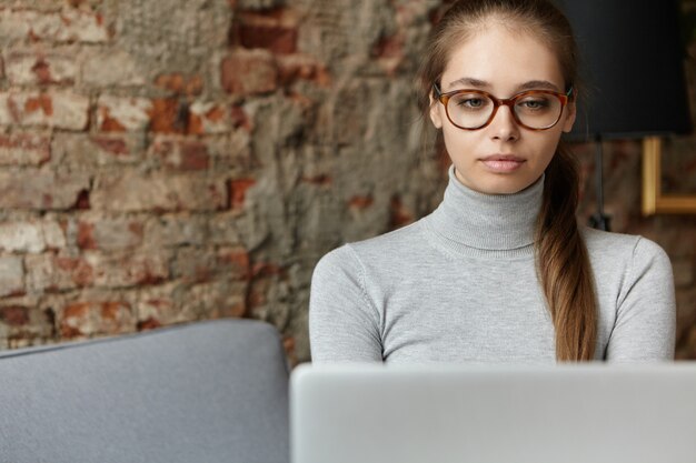 Young woman wearing grey turtleneck and eyeglasses