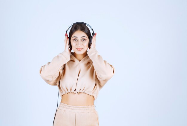 Young woman wearing headphones and listening to her playlist with enjoyment