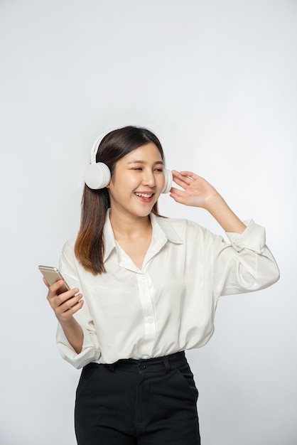 Young woman wearing headphones and listening to music on a smartphone