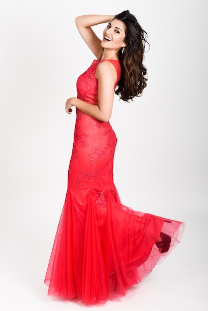 Young woman wearing long red dress on white background. 