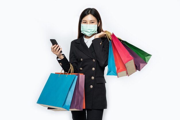 Молодая женщина в маске и покупок на своем смартфоне