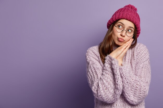 紫色のセーターと帽子をかぶった若い女性