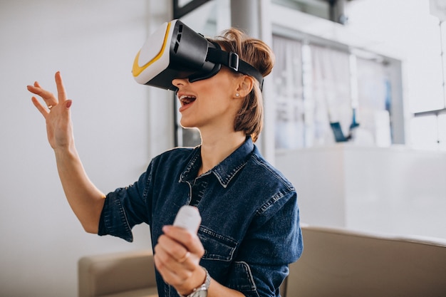 VR 안경을 착용하고 원격을 사용하여 가상 게임을하는 젊은 여자