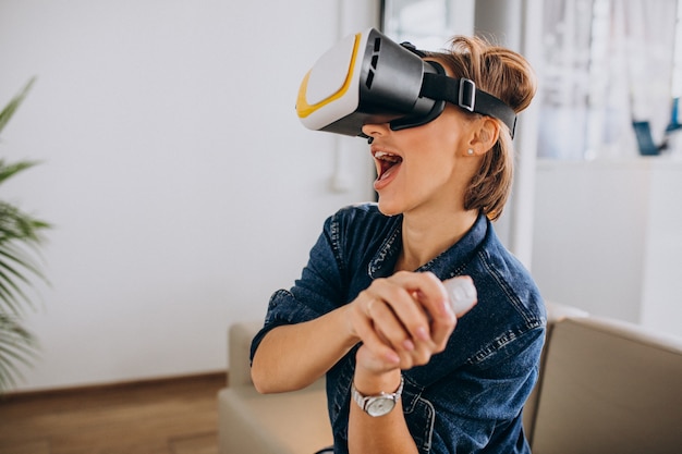 VR 안경을 착용하고 원격을 사용하여 가상 게임을하는 젊은 여자