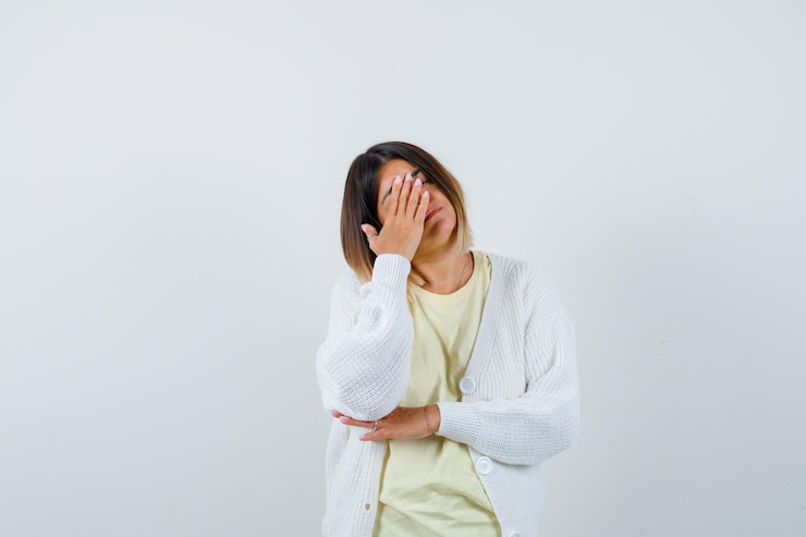 무료 Photo 그녀의 얼굴을 덮고 흰색 가디건을 입고 젊은 여자