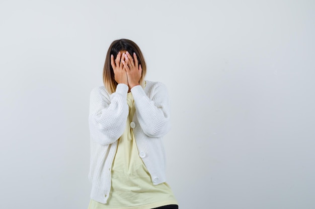 Foto gratuita giovane donna che indossa un cardigan bianco che le copre il viso