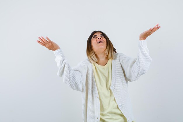 Young woman wearing a white cardigan with hands up