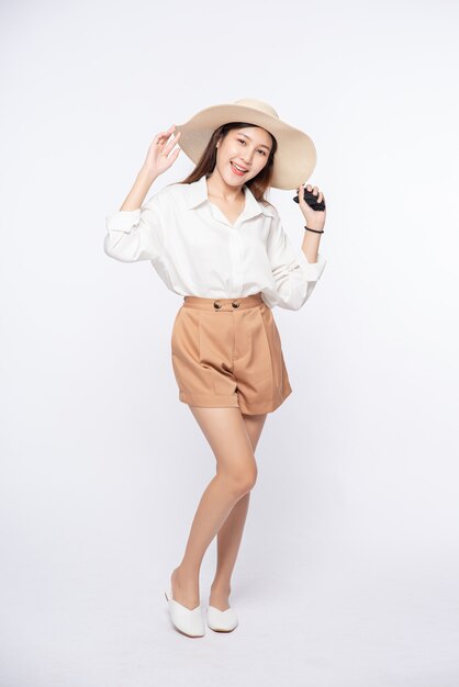 Young woman wearing a white shirt and shorts, wearing a hat and handle on the hat