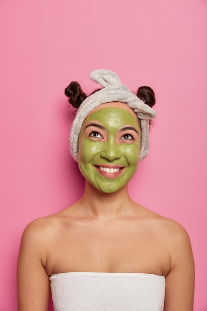 Молодая женщина носит натуральные маски для лица для ухода за кожей после принятия ванны