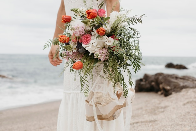 Giovane donna in abito da sposa in spiaggia