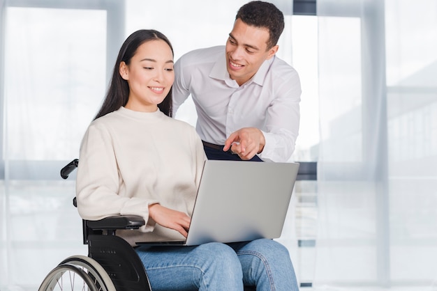 Young woman in wheelchair working with a male colleague