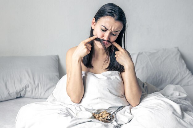 Una giovane donna a letto bianco con cereali e latte