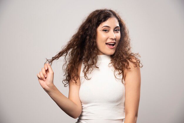 Young woman in white blouse standing over a white wall. High quality photo