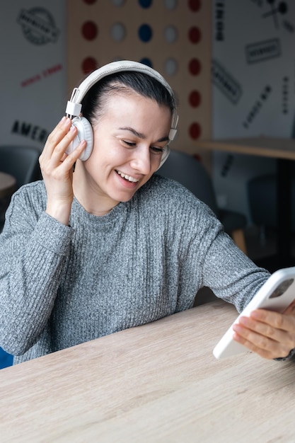 Foto gratuita una giovane donna in cuffie bianche e con uno smartphone