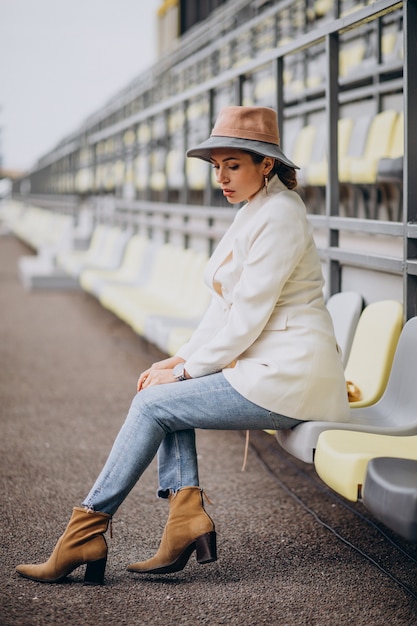 Young woman in white jacket holding hat