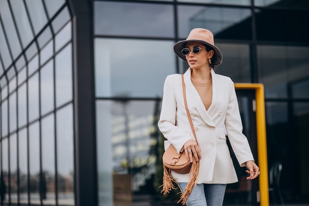 Free photo young woman in white jacket walking outdoors