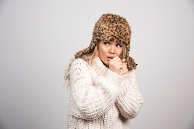 Young woman in white knitted sweater looking scared. 