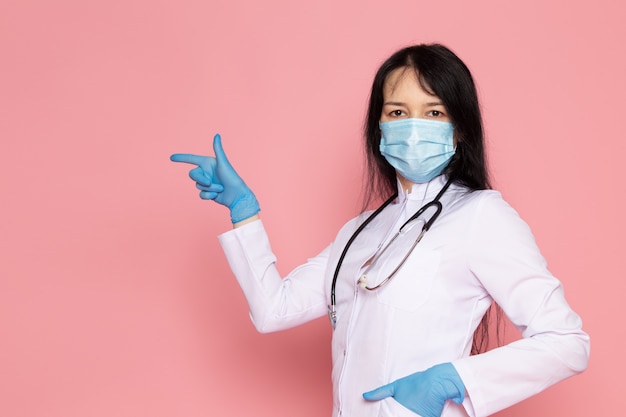 young woman in white medical suit blue gloves blue protective mask on pink