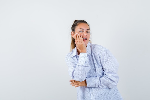 Young woman in white shirt holding hand near mouth while posing and looking cute