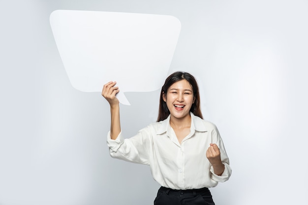 A young woman in a white shirt holding a thought box symbol