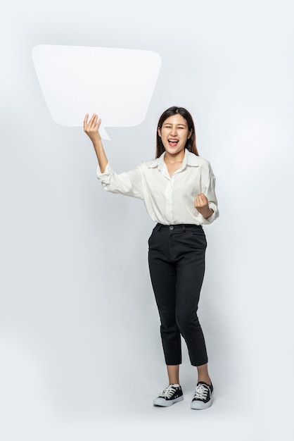 A young woman in a white shirt holding a thought box symbol