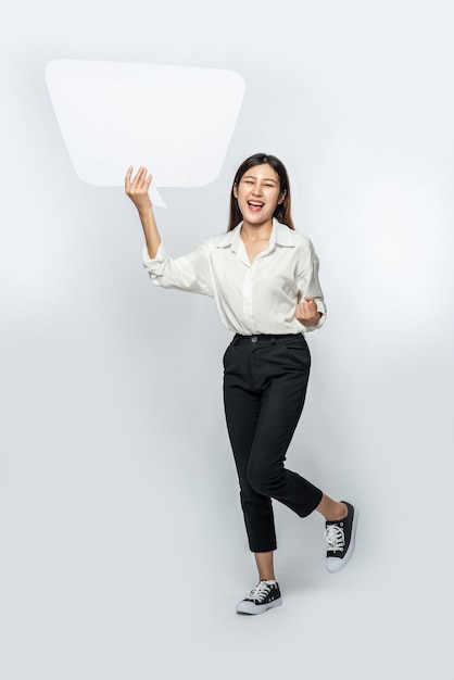 A young woman in a white shirt holding a thought box symbol