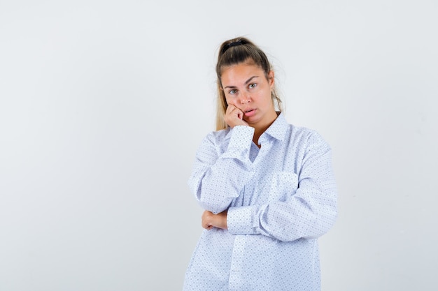 Young woman in white shirt leaning cheek on fist and looking cute