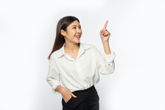A young woman in a white shirt and pointing up