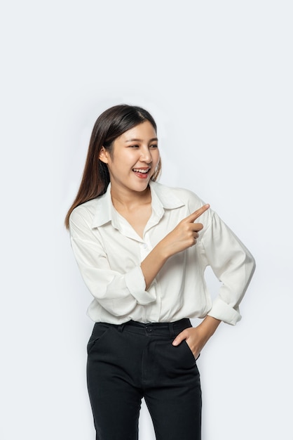 A young woman in a white shirt and pointing up