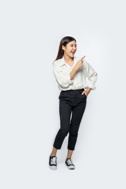 A young woman in a white shirt and pointing up