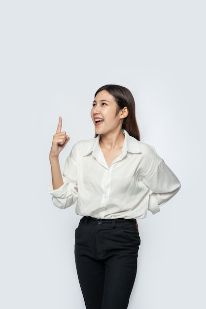 Free photo a young woman in a white shirt and pointing up