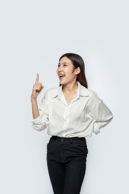 A young woman in a white shirt and pointing up