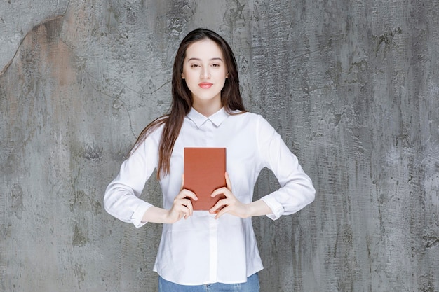 책을 보여주는 흰 셔츠에 젊은 여자. 고품질 사진