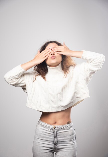 Young woman in white sweater closing her eyes. High quality photo