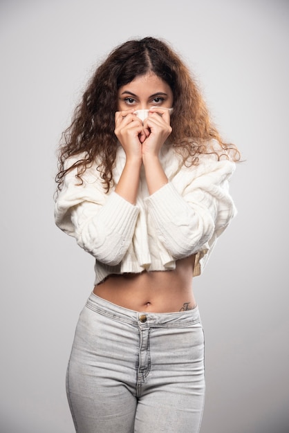 Young woman in white sweater standing over a white wall. High quality photo