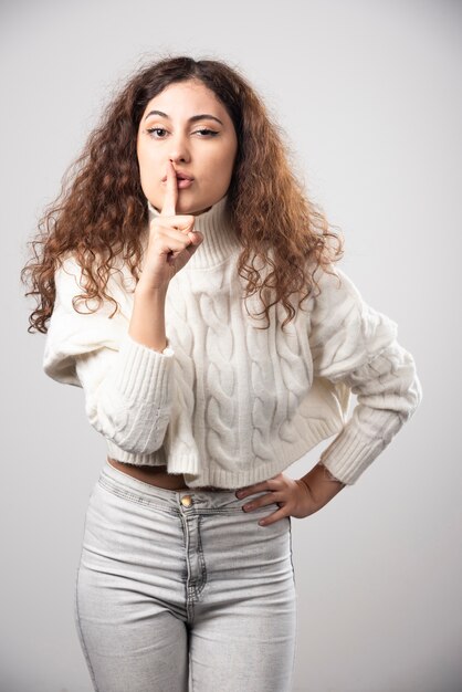 Young woman in white sweater standing over a white wall. High quality photo