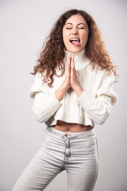 Young woman in white sweater standing over a white wall. High quality photo