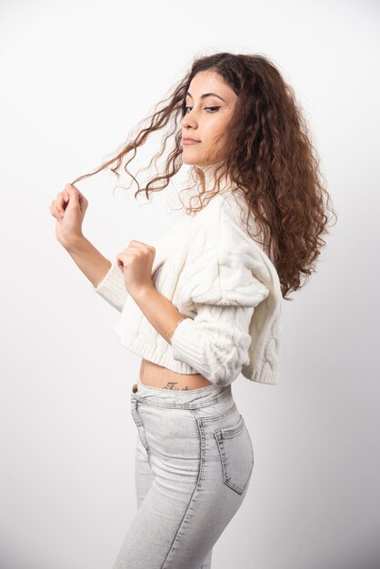 Young woman in white sweater standing over a white wall. High quality photo