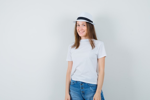 Young woman in white t-shirt, shorts, hat and looking delightful.
