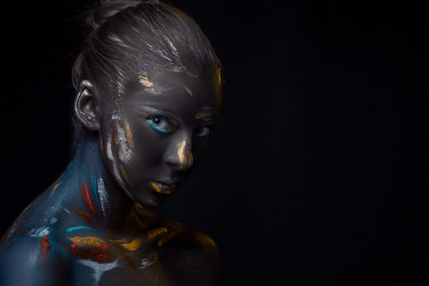 young woman who is posing covered with  black paint