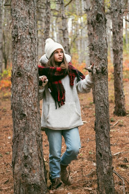 Young woman in winter clothes standing next to trees