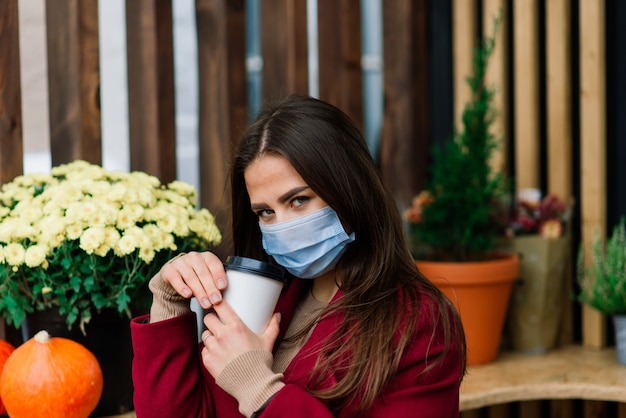レストラン​で​フェイス​マスク​を​持つ​若い​女性​、​コロナ​ウイルス​の​パンデミック​を​保護する​ため​の​新しい​通常​の​概念