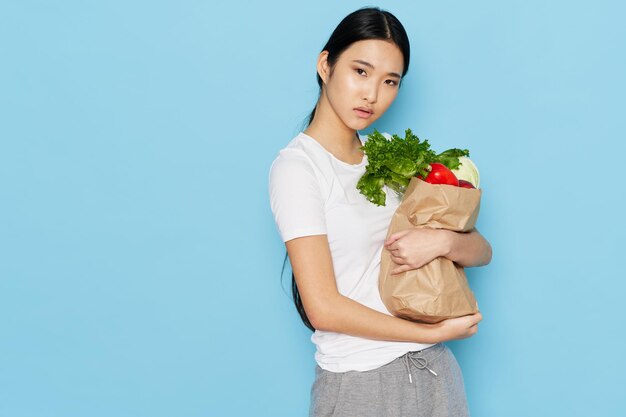 青い背景のダイエットカロリー健康的なライフスタイルの製品のパッケージを持つ若い女性 Premium写真