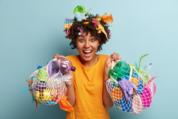 Young woman with Afro haircut holding bag with plastic waste