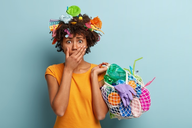 Foto gratuita giovane donna con taglio di capelli afro che tiene il sacchetto con i rifiuti di plastica