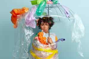 Free photo young woman with afro haircut holding bag with plastic waste